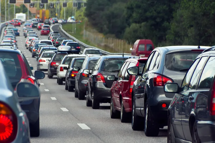Trafic intens pe o autostradă din România, cu multe autoturisme parcate.