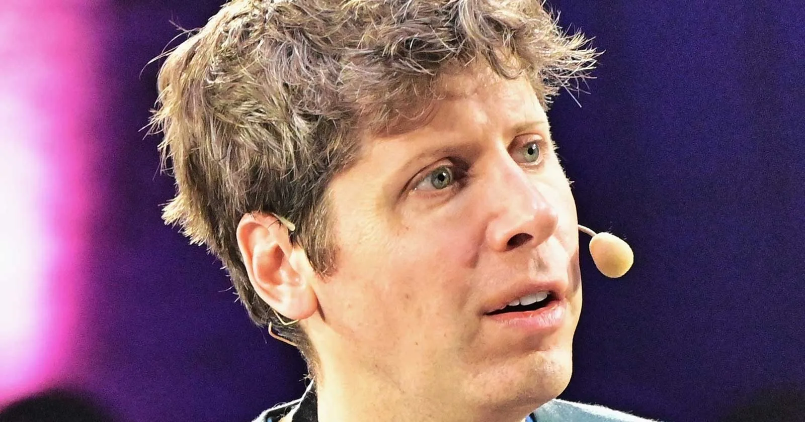 Un bărbat cu păr ondulat și microfon pe față, discutând despre tehnologie.