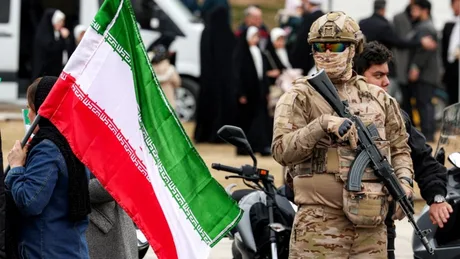 Soldat iranian în uniformă, cu steagul Iranului în fundal.