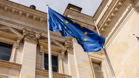 Steagul Uniunii Europene fluturând în fața unei clădiri oficiale.