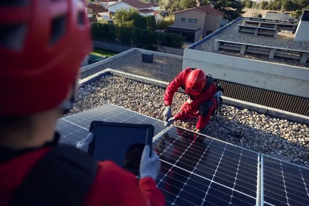Specialiști instalând panouri fotovoltaice pe o clădire modernă.