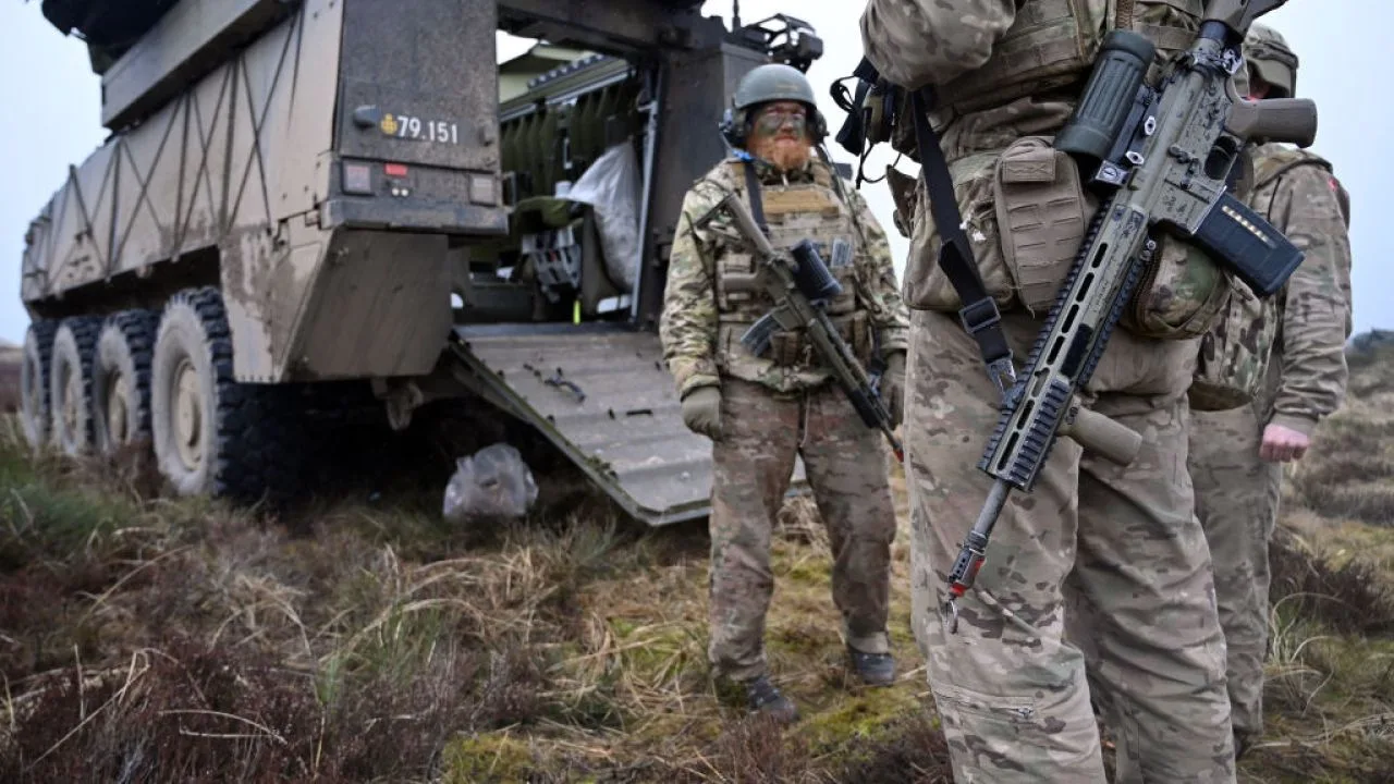 Soldați în uniformă militară, pregătiți pentru exerciții de apărare în teren accidentat.