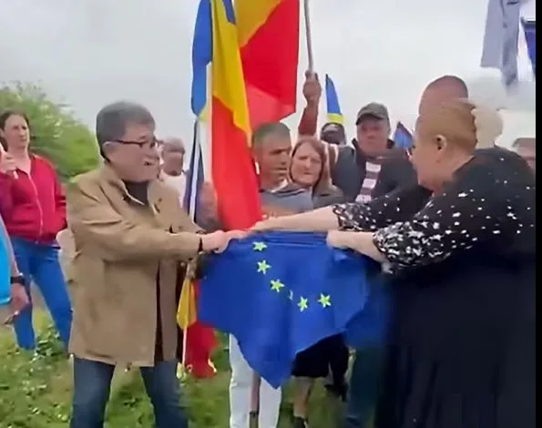 Protest cu steaguri românești și europene, oameni în discuție aprinsă.