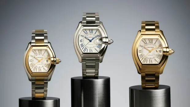 Trei modele de ceasuri Cartier pe suport metalic, cu design elegant și sofisticat.
