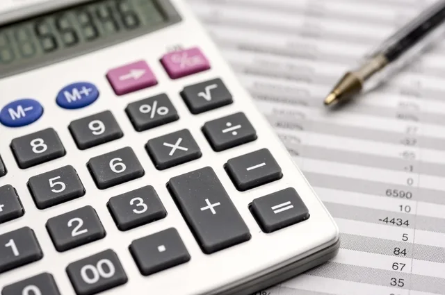 Calculator și documente financiare pe birou, simbolizând pierderi și bilanțuri.