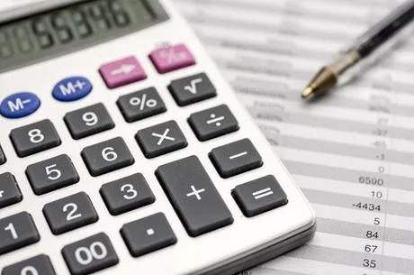 Calculator și documente financiare pe birou, simbolizând pierderi și bilanțuri.
