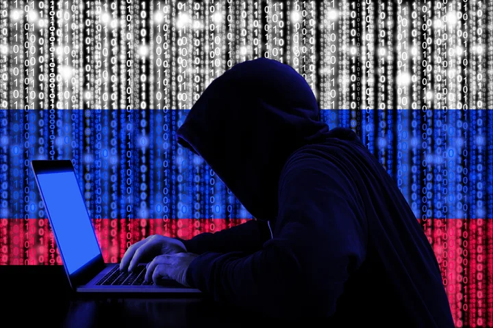 Un hacker lucrează la un laptop, în fața unui fundal cu simboluri cibernetice.