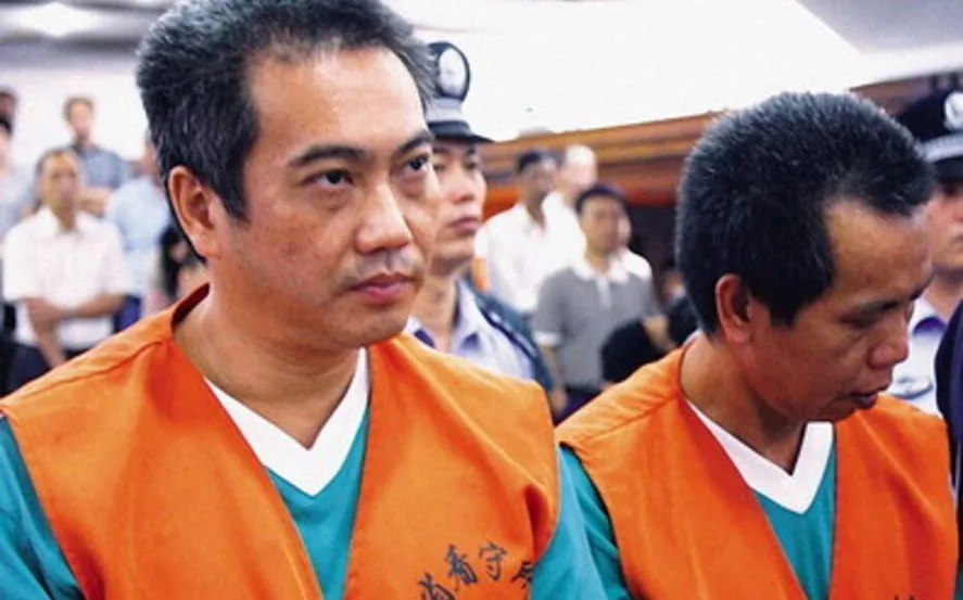 Doi bărbați în haine de detenție, în timpul unei ședințe de judecată.