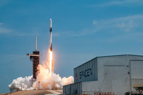 Racheta SpaceX decolează de pe platforma de lansare, însoțită de fum alb.