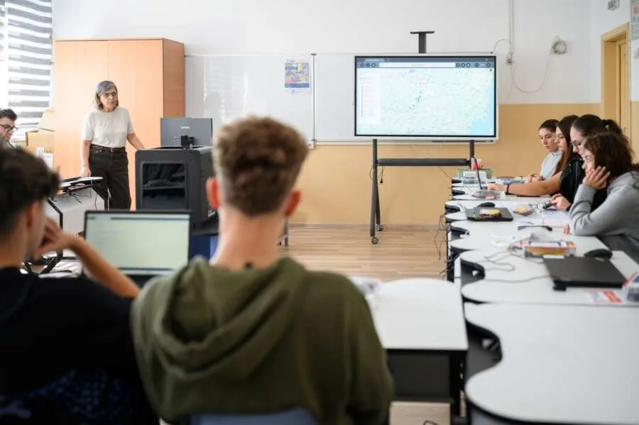 O sală de clasă modernă cu elevi și un profesor la tablă.