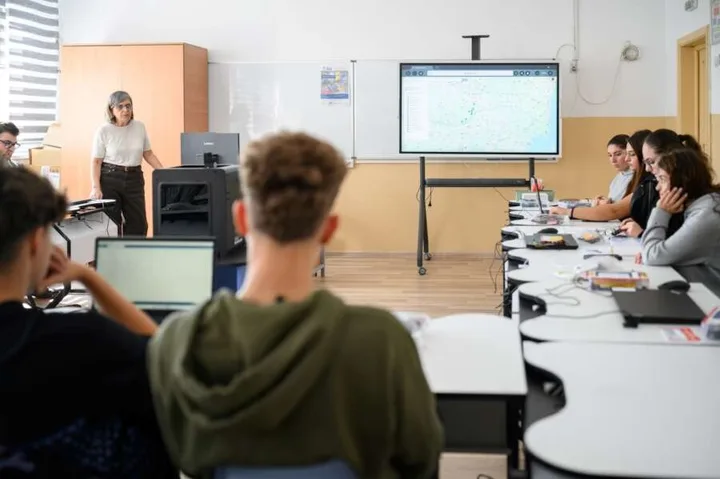 O sală de clasă modernă cu elevi și un profesor la tablă.