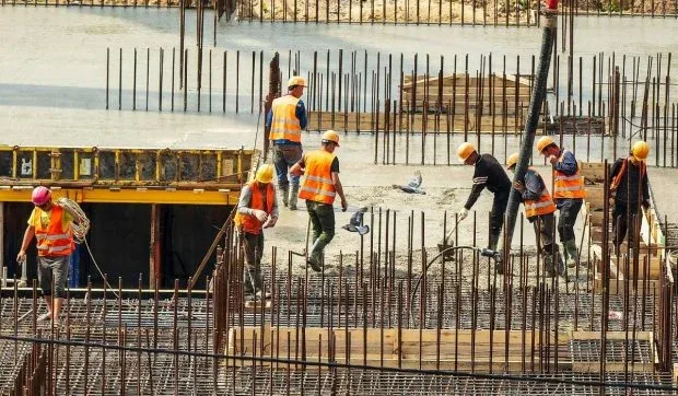 Muncitori români angajați în construcții, lucrând pe un șantier.