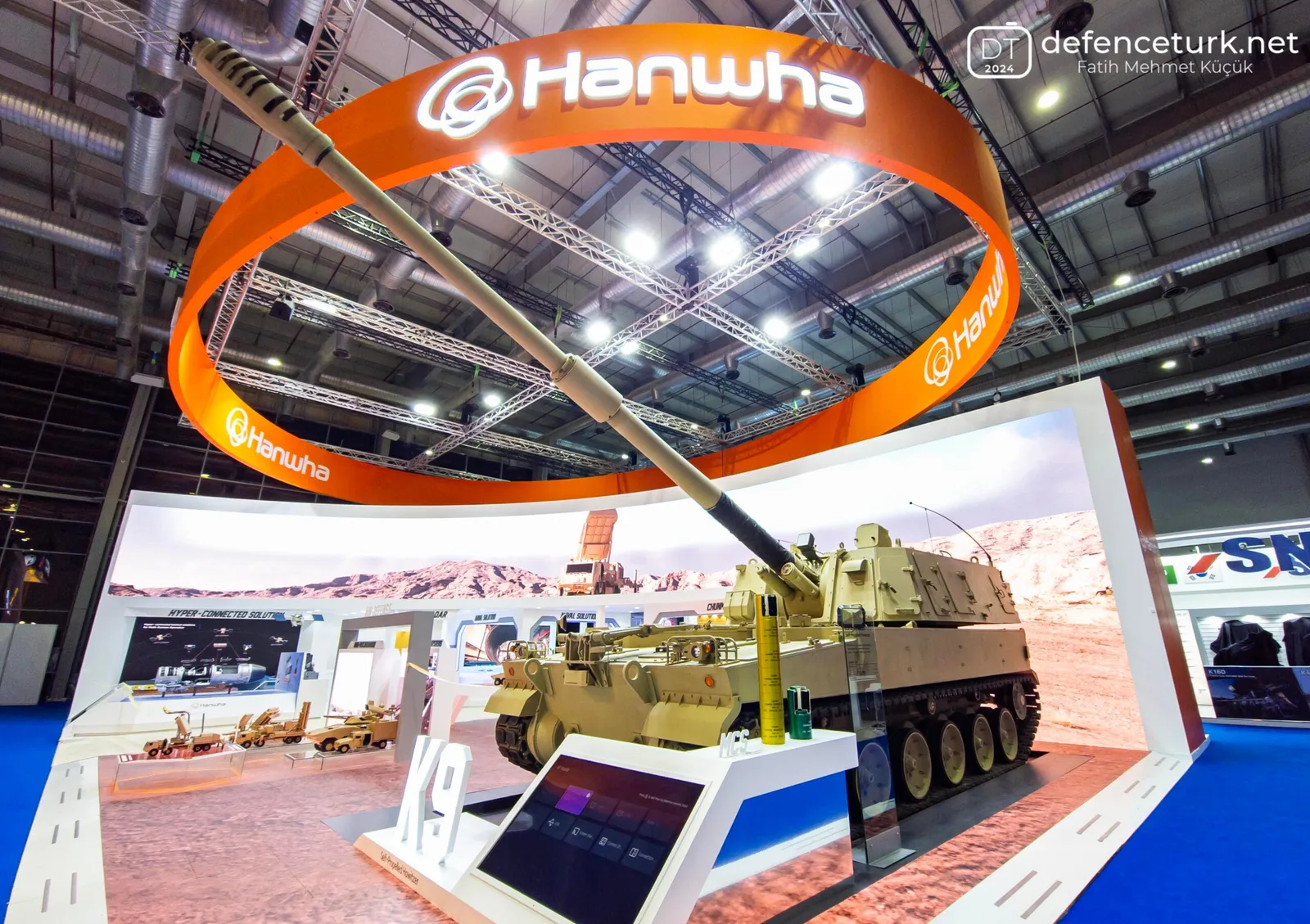Standul Hanwha Aerospace cu vehiculul blindat K9 la un târg de apărare.