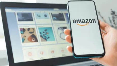 Un telefon mobil cu logo-ul Amazon lângă un laptop deschis.
