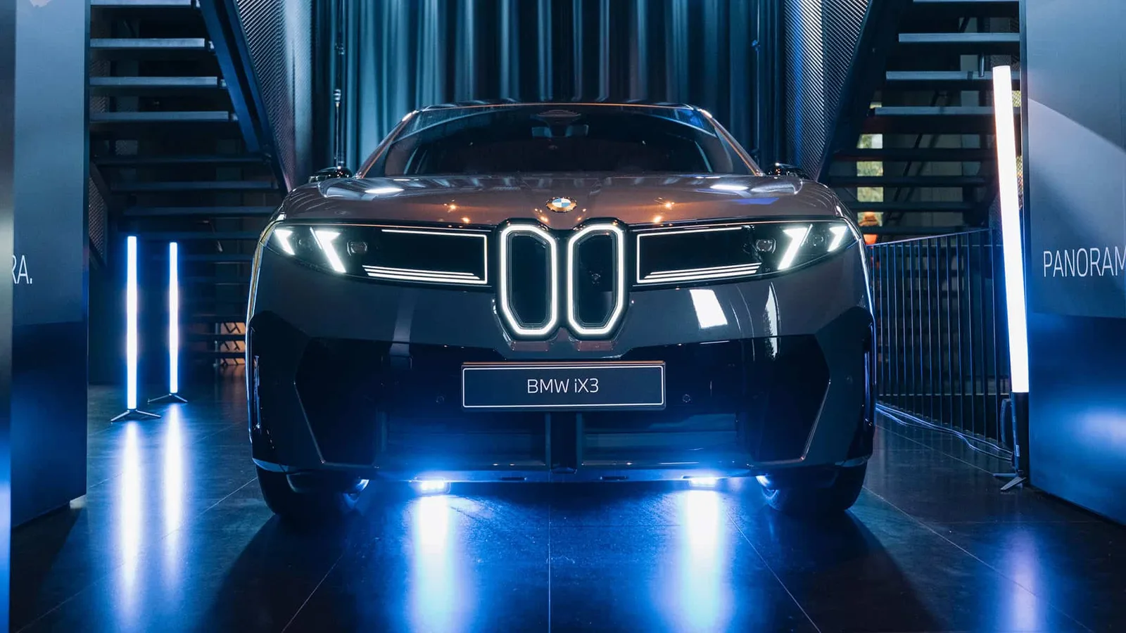 BMW IX3 expus într-un showroom modern, cu lumini strălucitoare.