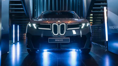 BMW IX3 expus într-un showroom modern, cu lumini strălucitoare.