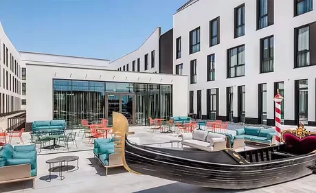 Terasa hotelului Hampton by Hilton din Veneția, cu mobilier modern și o gondolă decorativă.