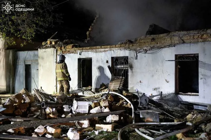 Ruinele unei clădiri distruse, cu un pompier în prim-plan.