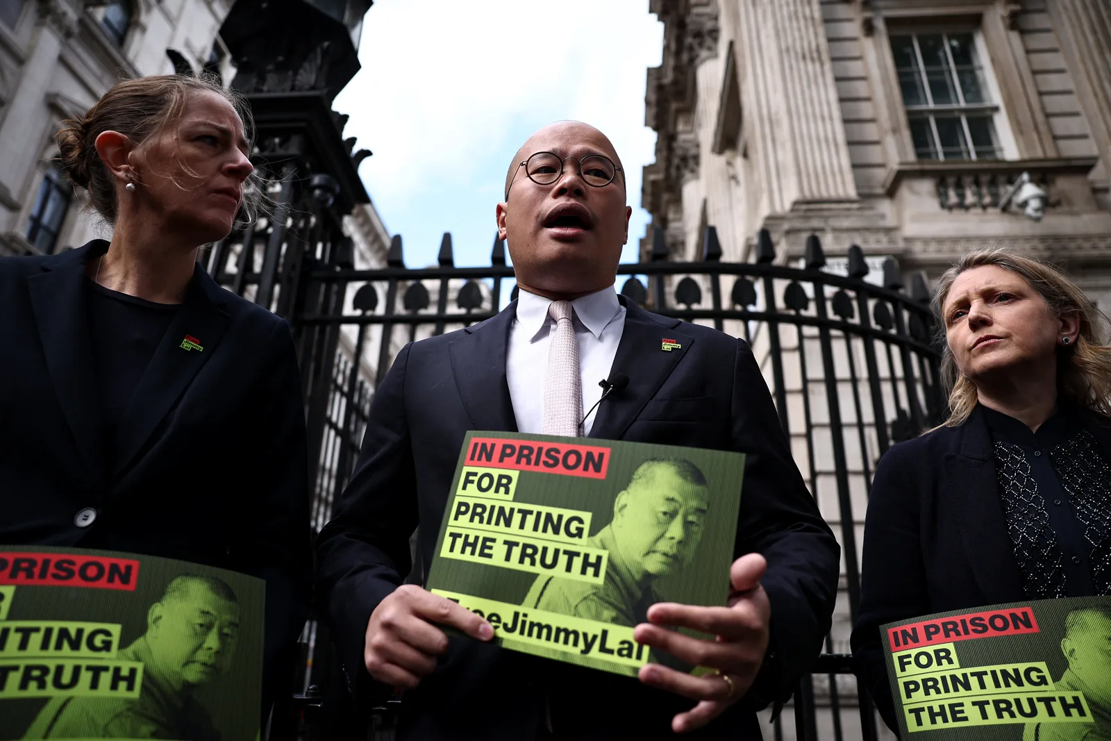 Activist pro-democrație discutând despre situația lui Jimmy Lai în fața unei clădiri guvernamentale.