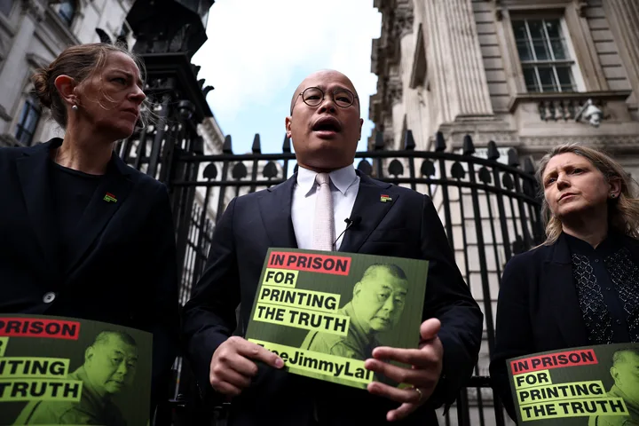 Activist pro-democrație discutând despre situația lui Jimmy Lai în fața unei clădiri guvernamentale.