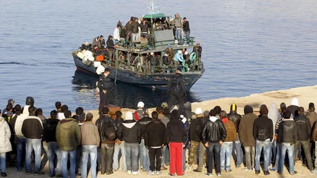 Grup de imigranți pe o barcă, în fața autorităților de coastă.