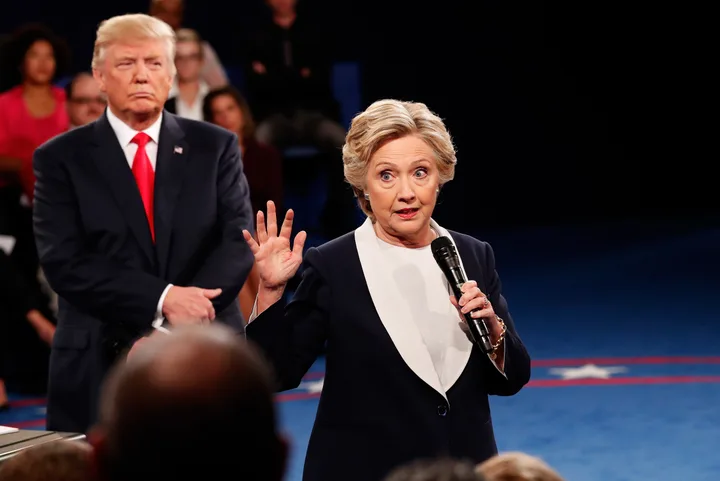 Hillary Clinton vorbește la o conferință, în fața lui Donald Trump.