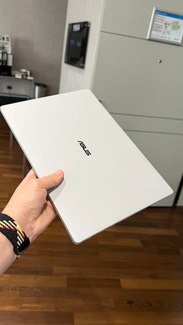 Laptopul ASUS ExpertBook Ultra ținut în mână, evidențiind designul subțire.