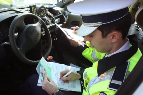Instructor auto verificând documente în mașină, în timpul examenului.