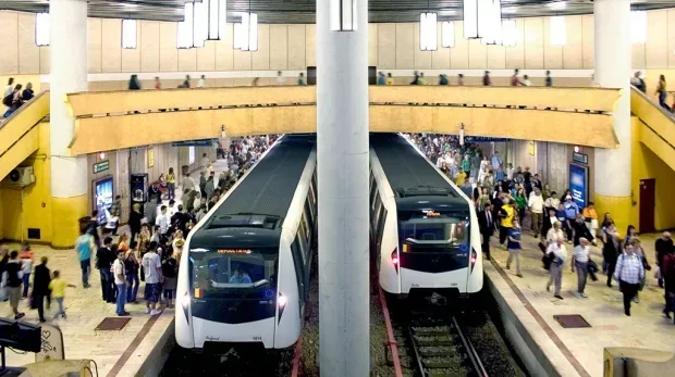 Stație de metrou aglomerată, cu trenuri în așteptare și călători.