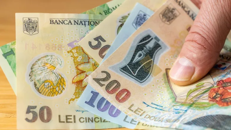 Bancnote românești de diferite valori, ținute în mână.