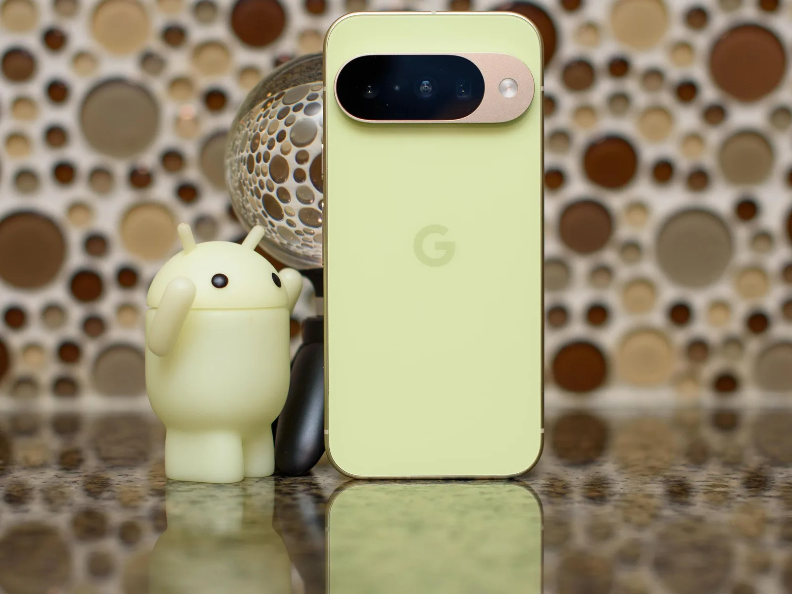 Un smartphone verde cu logo Google și figurina Android.