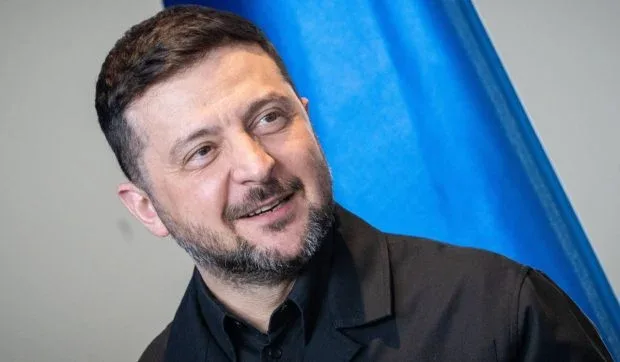 Lider ucrainean zâmbind în fața unui steag al țării.