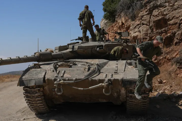 Soldați israelieni inspectând un tanc pe teren accidentat.