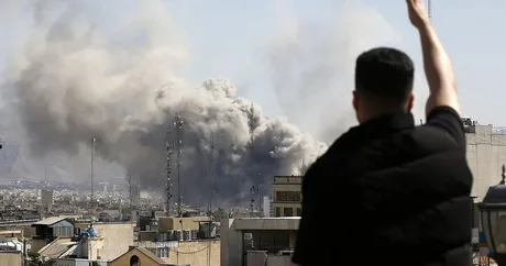 Fum gros se ridică deasupra unui oraș afectat de atacuri aeriene.