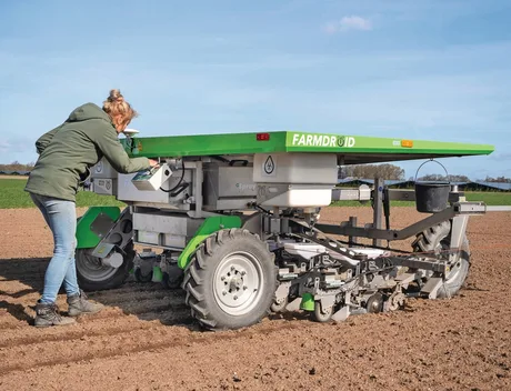 Fermier verificând robotul FarmDroid FD20 în câmpul de sfeclă de zahăr.