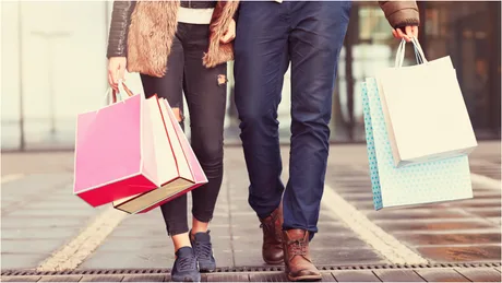 Tineri care fac cumpărături pe o stradă urbană aglomerată.