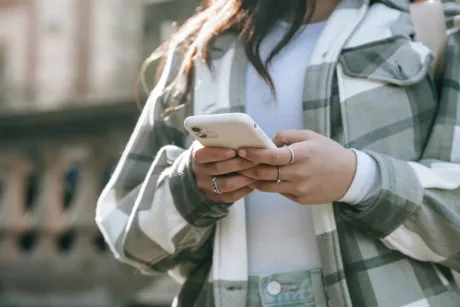 Persoană folosind un telefon mobil în exterior.