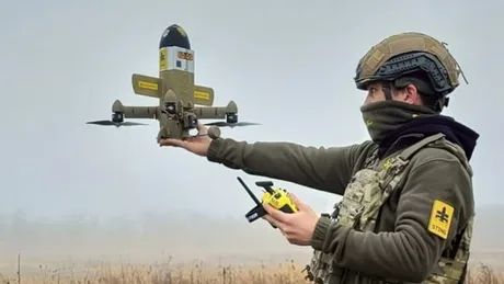 Un soldat controlează o dronă pe câmpul de luptă, evidențiind inovația militară modernă.