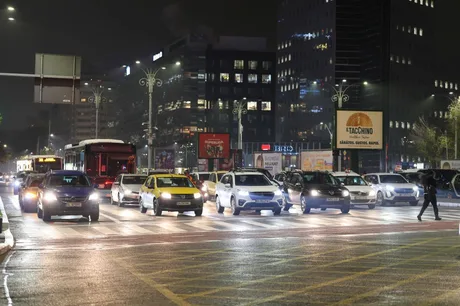 Intersecție aglomerată din București, cu vehicule și semafoare în fundal.