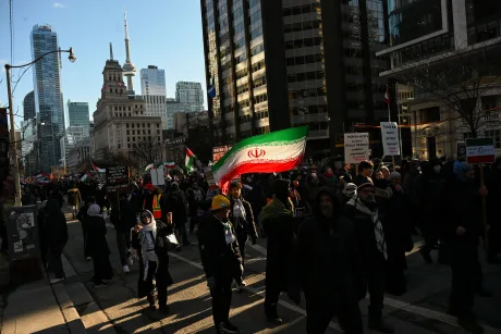 Protest în Toronto cu steaguri iraniene și participanți pe stradă.