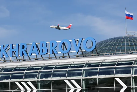 Aeroportul Khrabrovo din Kaliningrad, cu un avion în zbor și steagul Rusiei.