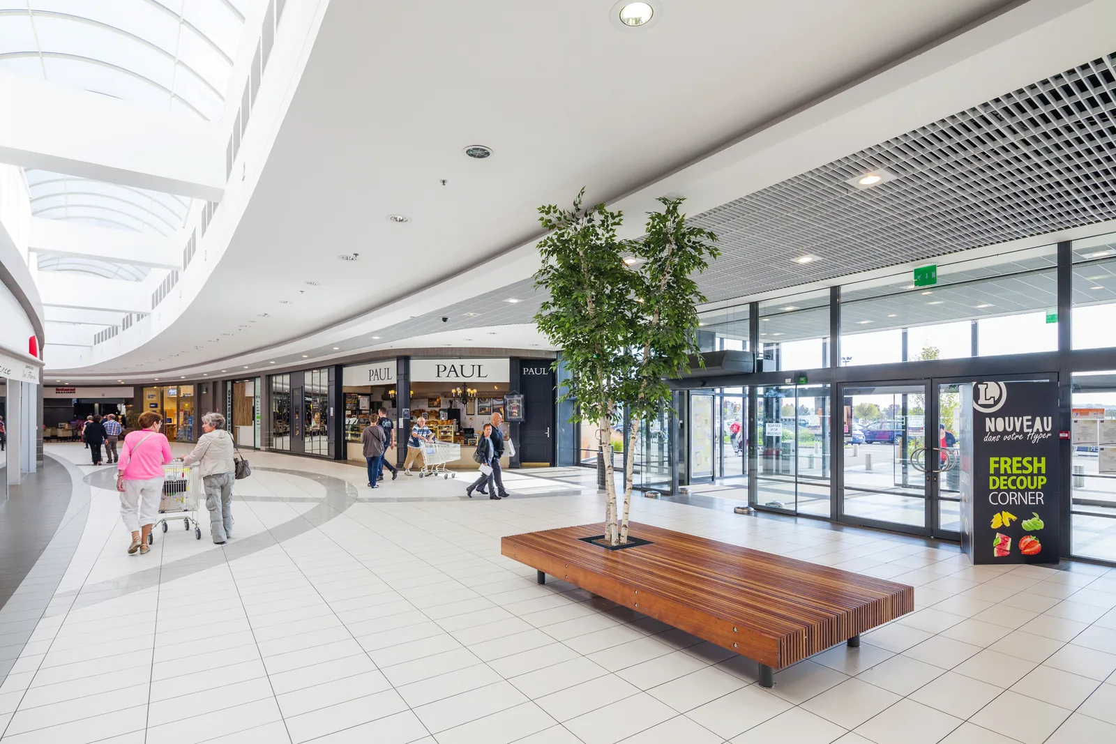 Interior modern al unui centru comercial din România, cu magazine și oameni.