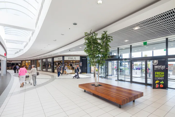 Interior modern al unui centru comercial din România, cu magazine și oameni.