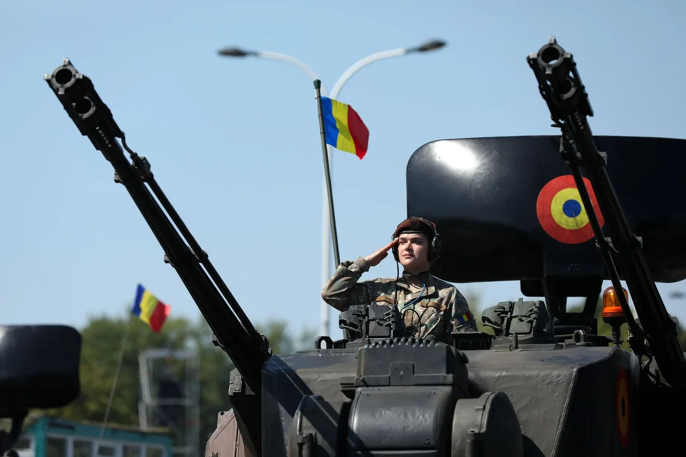 Soldat român pe un vehicul militar, salutând cu mândrie.
