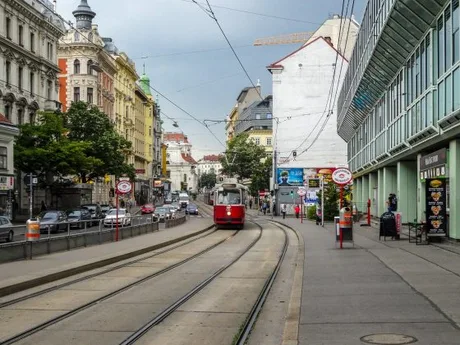 Stradă din Austria cu tramvai și clădiri istorice pe fundal.
