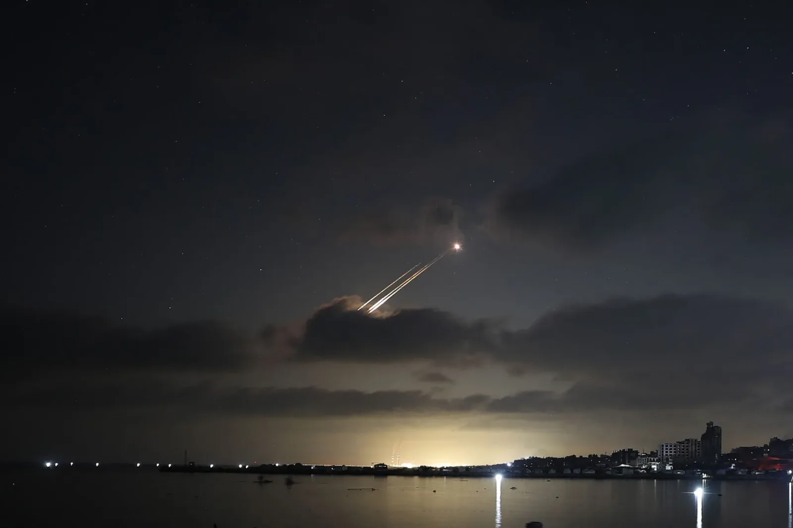 Rachete lansate în noapte, iluminate de focuri de artificii.