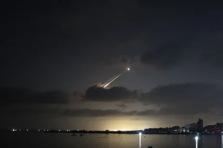 Rachete lansate în noapte, iluminate de focuri de artificii.