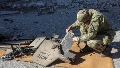 Soldat inspectând resturi ale unei drone distruse.