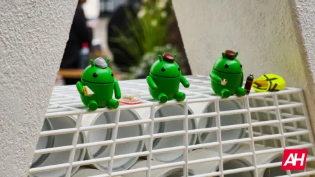 Figurine verzi Android cu pălării, așezate pe un suport alb.