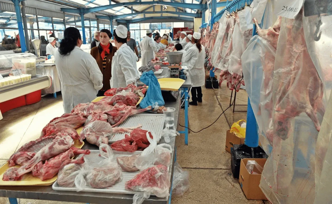 Stand cu carne proaspătă într-un market, clienți și vânzători activi.
